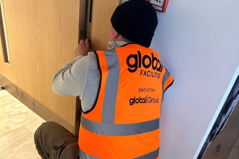 Global Facilities Inspector repairing a fire door